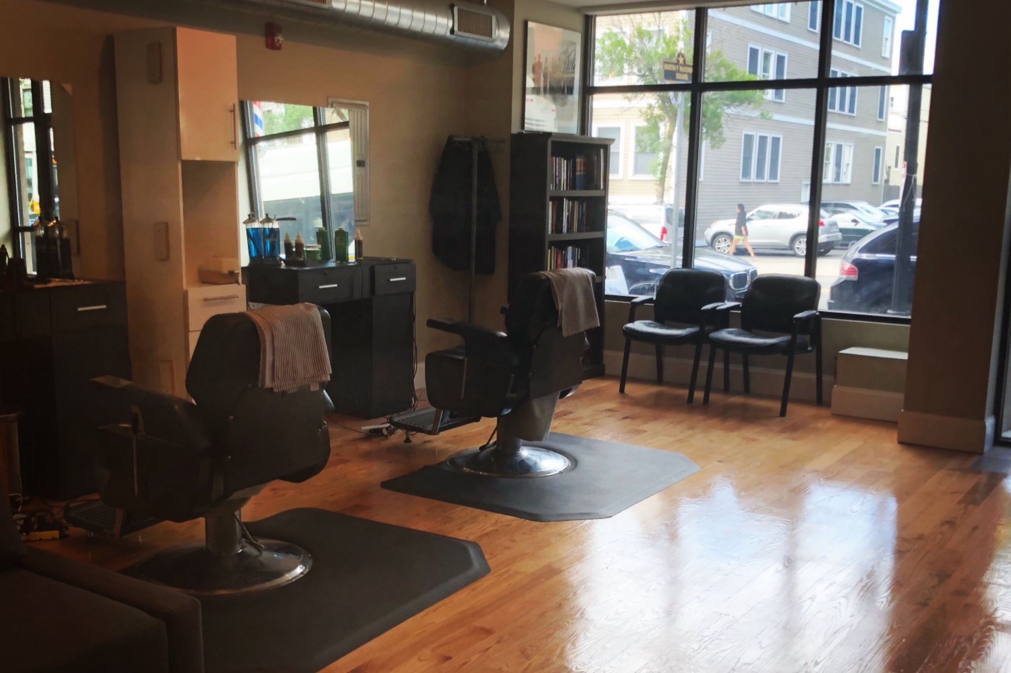 Inside LoGrasso's Barbershop: two barber chairs on a wood floor, storefront windows looking out on West Broadway